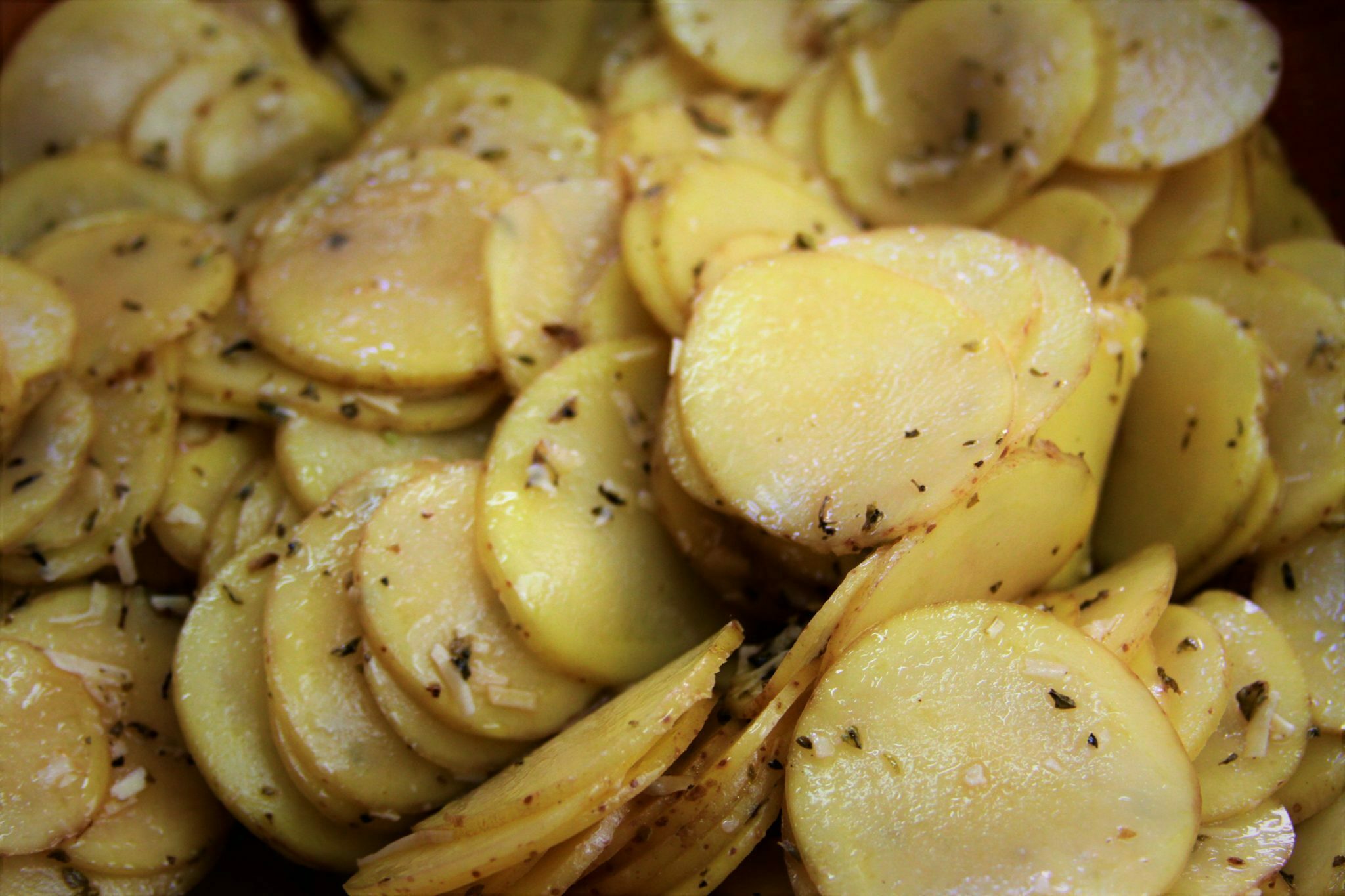 Batatas fatiadas temperadas com queijo parmesão, orégano e alho para mil folhas de batata