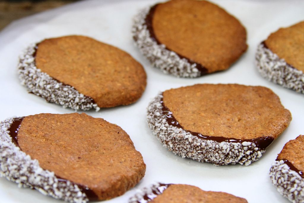 biscoito de coco e amendoim banhado no chocolate com coco seco secando papel manteiga - amor pela comida