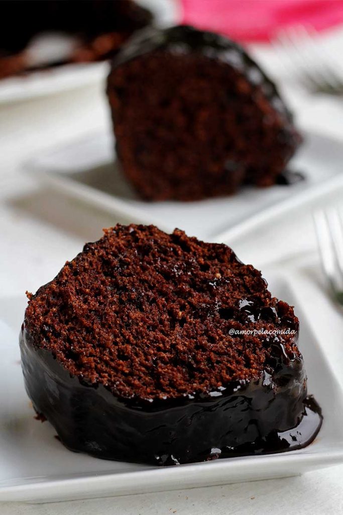 BOLO DE CHOCOLATE COM COBERTURA SEM GLÚTEN SEM LACTOSE Duas fatias de bolo de chocolate com cobertura de chocolate sobre prato branco