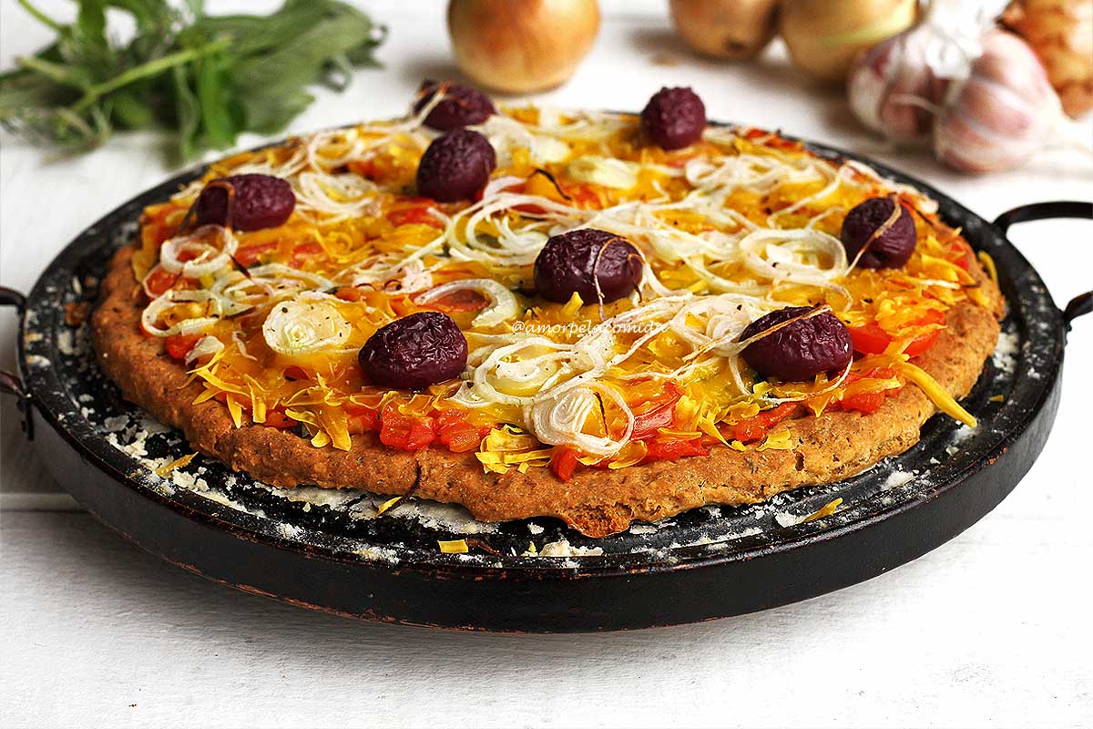 Pizza de queijo com tomate, azeitonas pretas e cebola sobre pedra de pizza em mesa branca