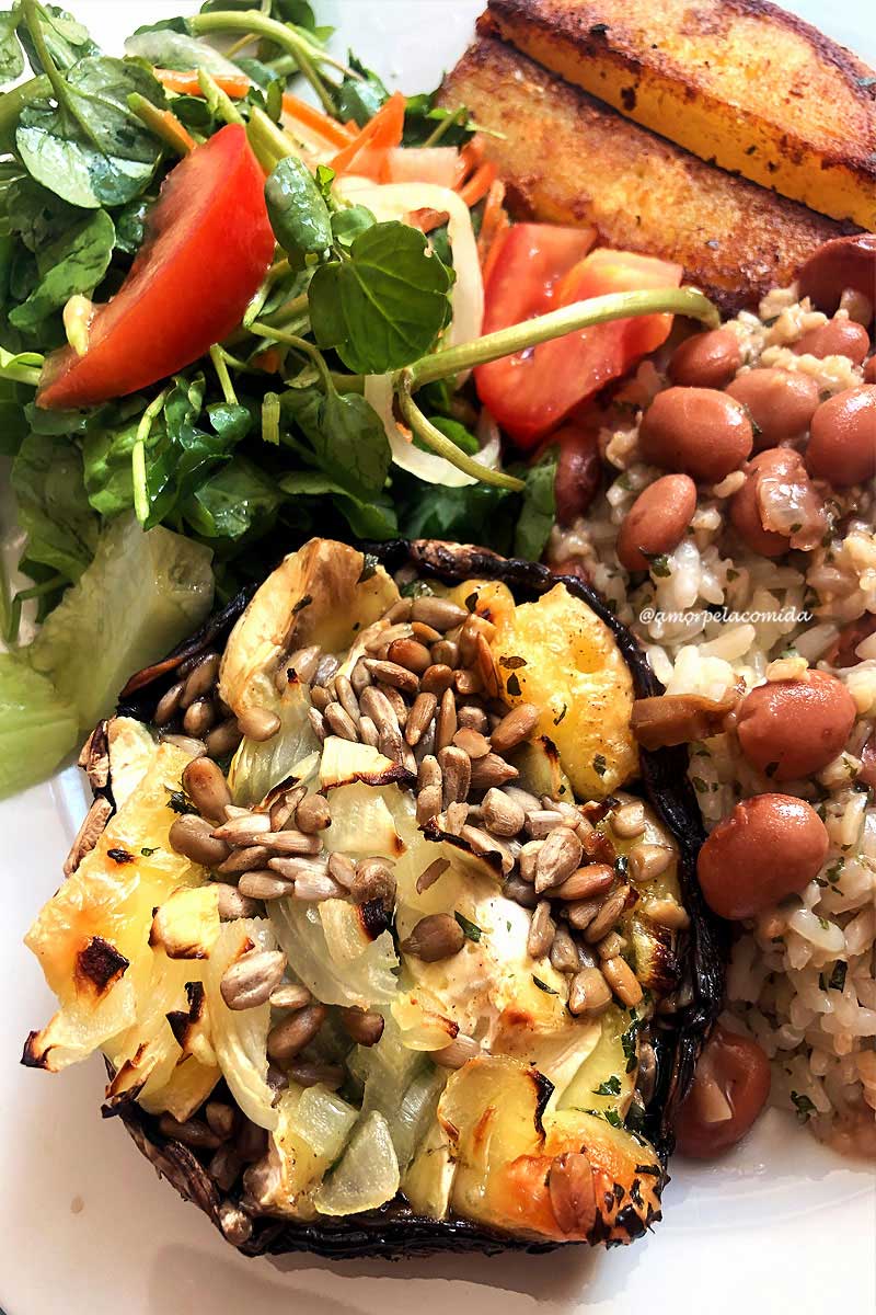 Prato de comida com cogumelo recheado, salada verde, feijão com arroz e batata dourada