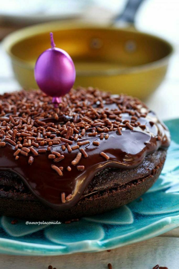 bolo redondo de chocolate com cobertura cremosa sobre prato azul