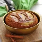 Frigideira dourada sobre tábua de madeira de cor clara em uma mesa branca