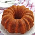 Bolo redondo com furo no meio e detalhes ondulados na lateral sobre prato branco