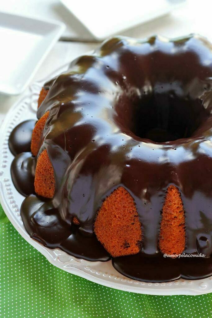 Bolo de cenoura redondo com furo no meio com cobertura cremosa de chocolate sobre um prato branco