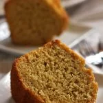 Duas fatias de bolo de fubá com maçã, a fatia da frente está deitada e a de trás está de pé desfocada