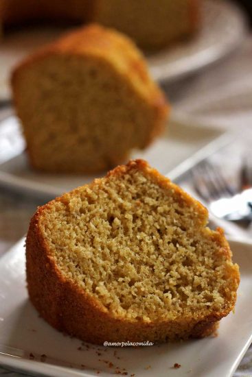 Duas fatias de bolo de fubá com maçã, a fatia da frente está deitada e a de trás está de pé desfocada