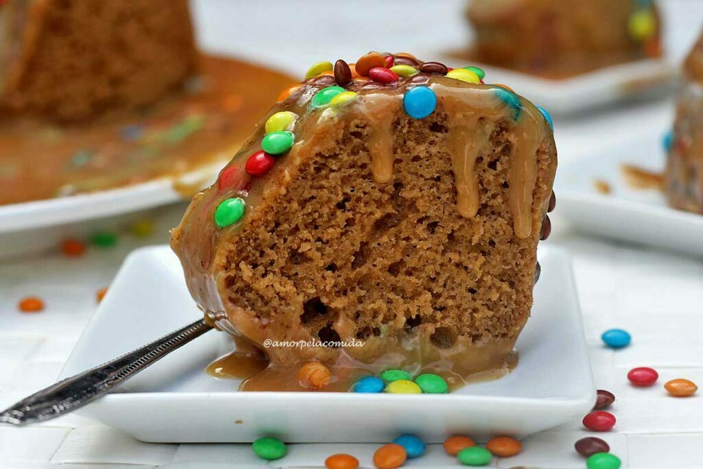 Fatia de bolo de churros com cobertura cremosa caramelizada e pequenos confeitos de açúcar coloridos