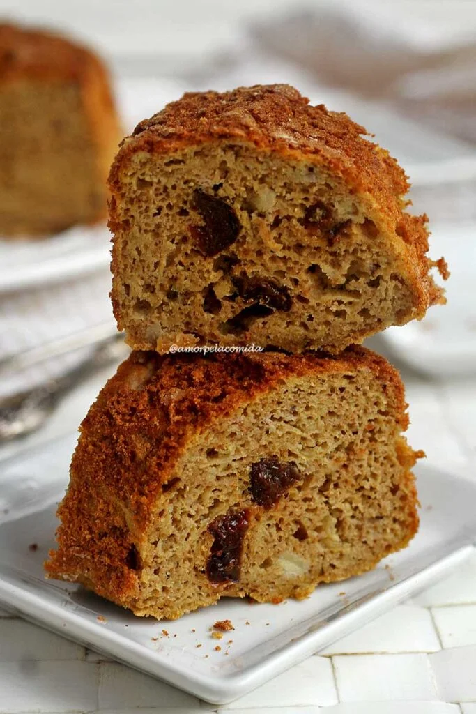 Duas fatias de bolo empilhadas sobre prato branco quadrado pequeno