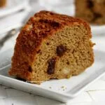 Fatia de bolo com pedacinhos de ameixa sobre prato quadrado pequeno