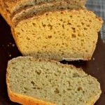 Pão fatiado sobre tábua de madeira escura