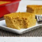 Duas fatias quadradas de bolo de fubá sobre pratos quadrados pequenos