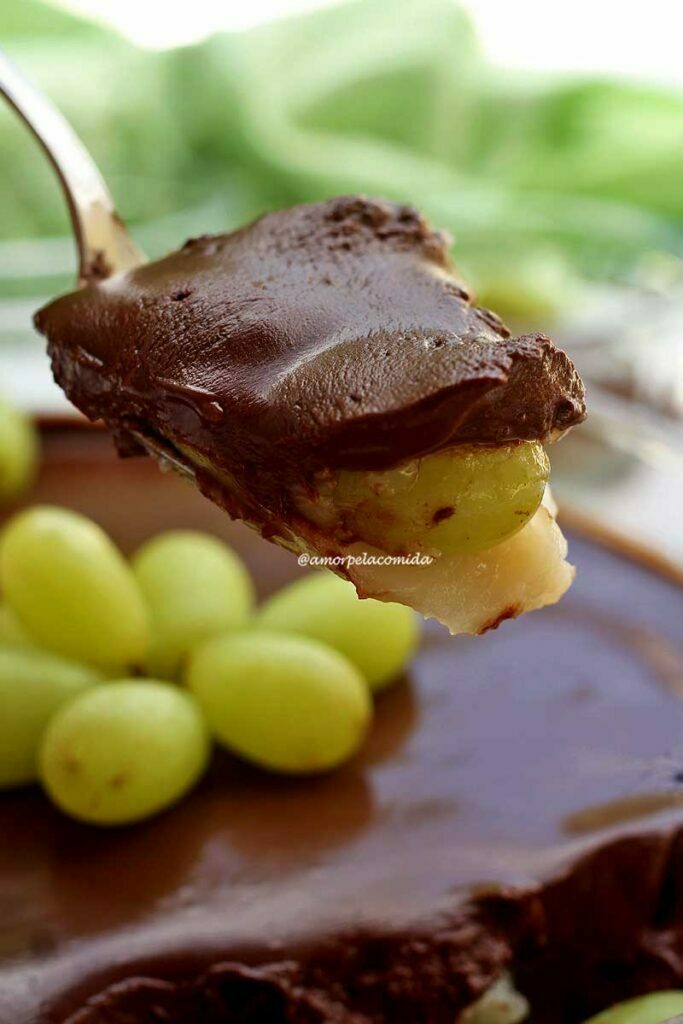 Colherada de sobremesa de uva, com creme de baunilha por baixo, uva no meio e chocolate cremoso por cima