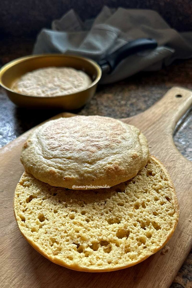 PÃO DE AVEIA E QUINOA DE FRIGIDEIRA Pão redondo cortado ao meio mostrando a textura aerada da massa, ao fundo a frigideira onde o pão foi assado