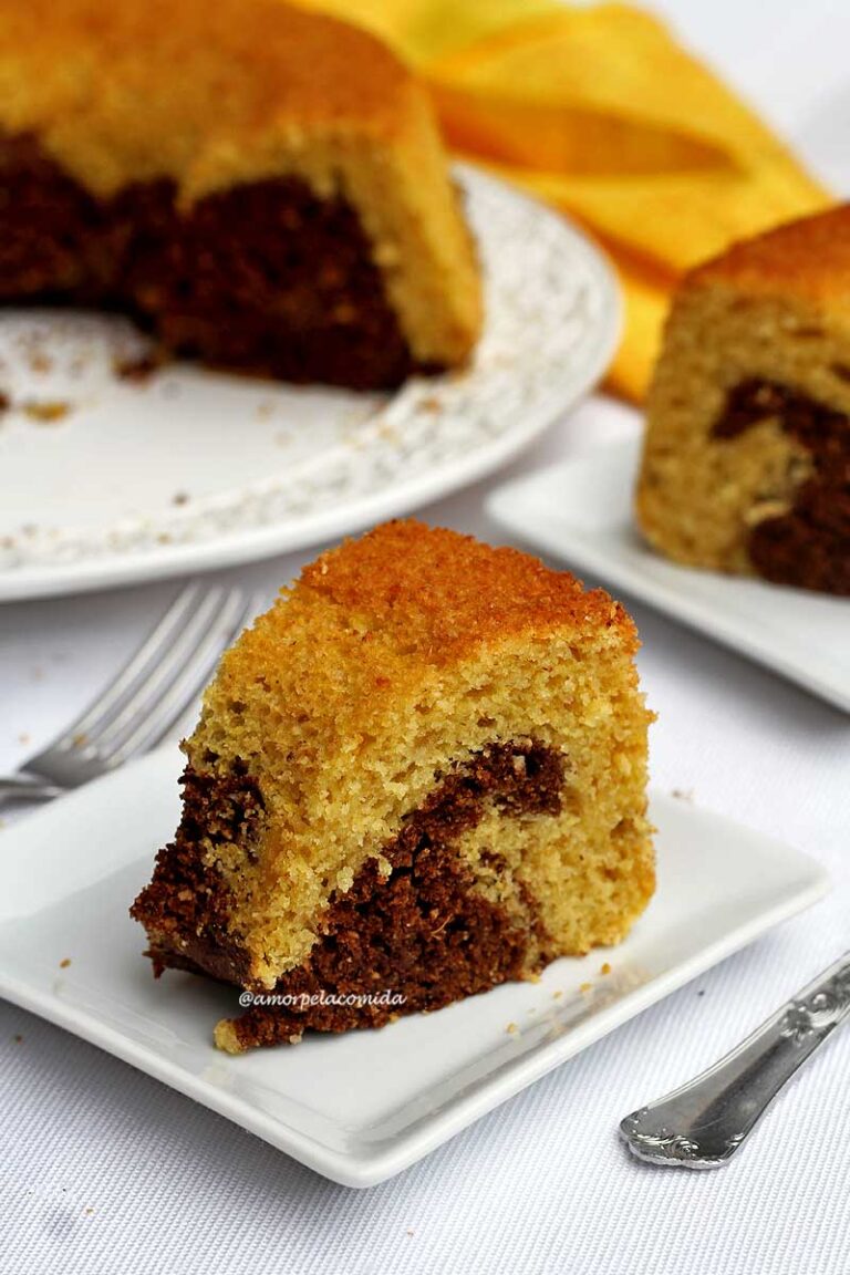 BOLO DE FUBÁ MESCLADO COM CHOCOLATE SEM TRIGO Duas fatias de bolo de fubá com uma parte mesclada de chocolate, os pedaços estão sobre 2 pratos pequenos quadrados