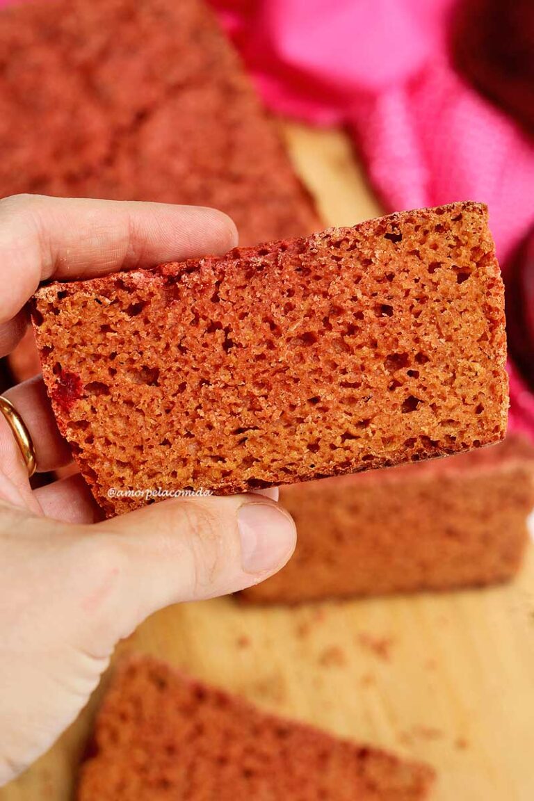 PÃO DE BETERRABA SIMPLES COM AVEIA Mão segurando fatia de pão de beterraba