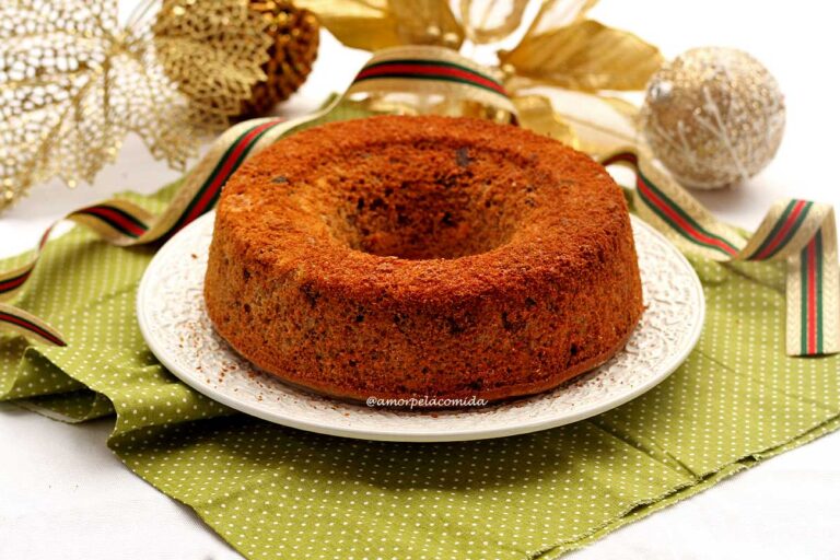 Bolo redondo com furo no meio, atrás decoração natalina de bolinhas e fita