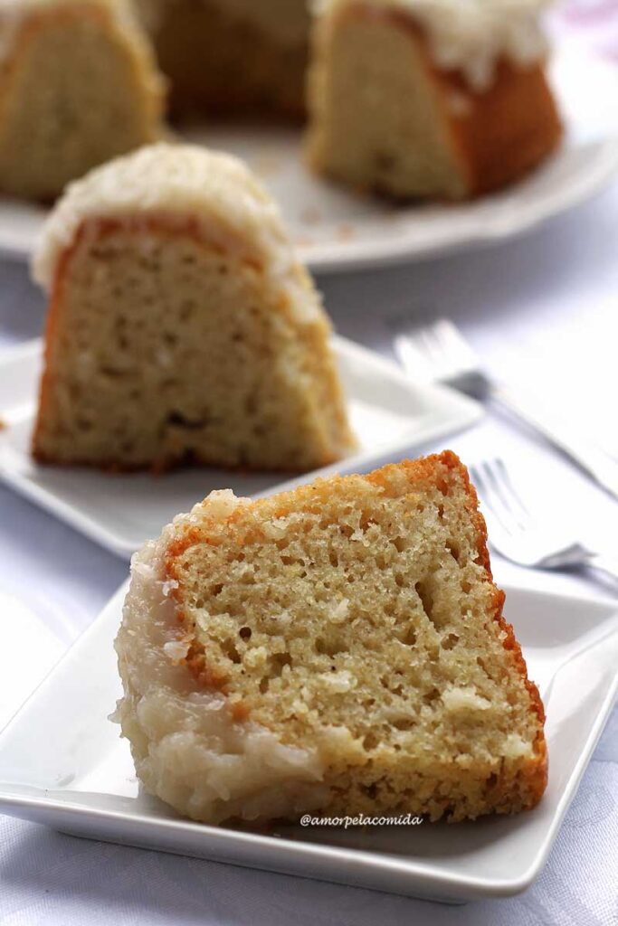 duas fatias de bolo de coco com cobertura de coco, a fatia da frente está deitada sobre o prato e a de trás está de pé sobre o prato