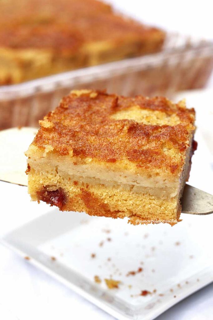 Espátula com uma fatia quadrada de bolo de fubá. Na parte de baixo da fatia um bolo fofinho, na parte de cima uma recheio cremoso de milho