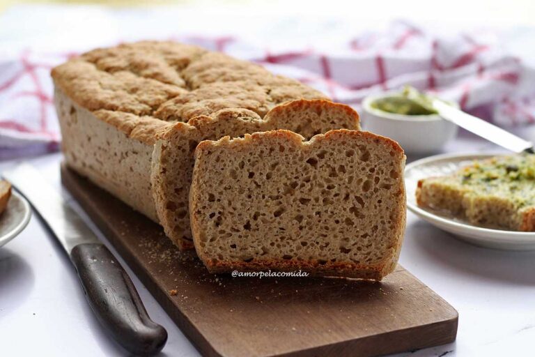 PÃO SEM GLÚTEN RECEITA SIMPLES E RÁPIDA Pão de forma com duas fatias cortadas apoiadas no pão e ao fundo uma fatia sobre prato redondo pequeno já com duas mordidas