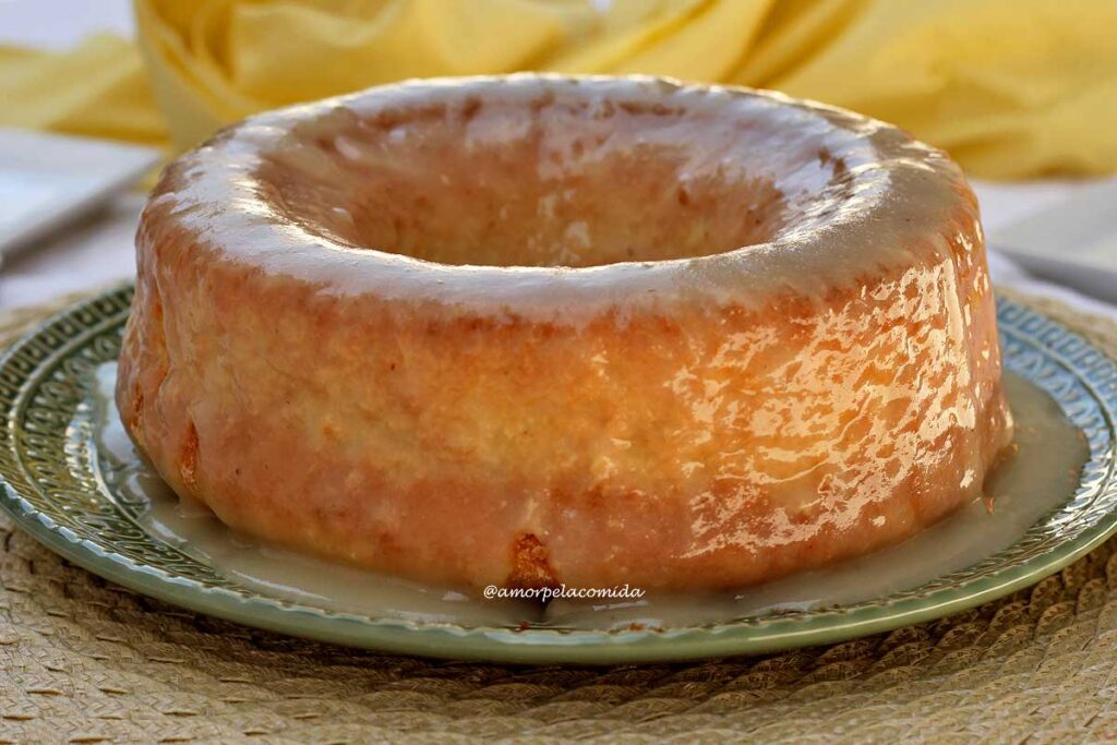 Bolo redondo com furo no meio coberto por uma cobertura brilhante e cremosa de abacaxi