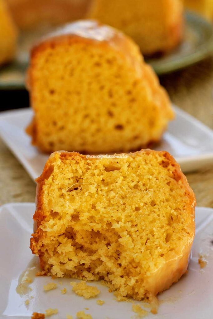 duas fatias de bolo de fubá com abacaxi, a de trás está de pé em um prato quadrado pequeno e a da frente está deitada sobre o prato e já comida, faltando uns 2 pedaços