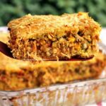 Fatia de torta de frango na espátula sobre a torta de frango que foi assada em uma forma de vidro canelado