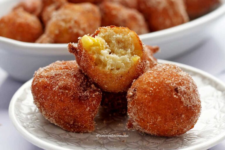 Três bolinho de chuva em um prato redondo pequeno, o que está por cima, está mordido