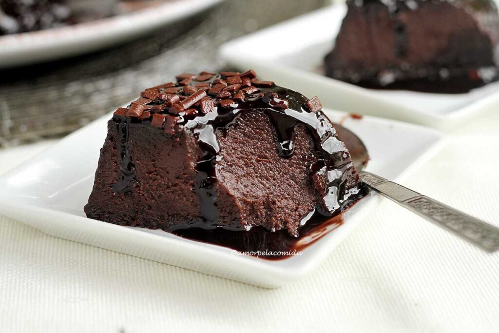 fatia de pudim de chocolate com calda de chocolate e cobertura de granulado de chocolate já faltando uma colherada da fatia