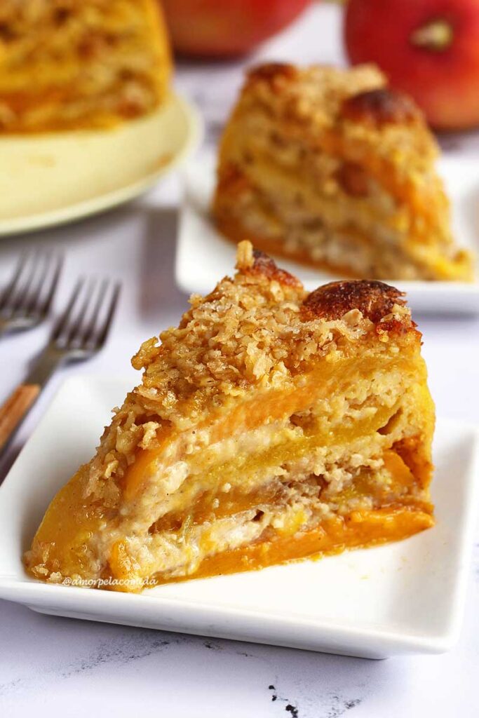 Fatia de torta de manga sobre prato quadrado pequeno, ao fundo mais um pedaço e uma parte da torta