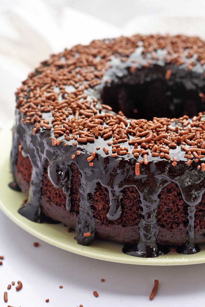 Bolo redondo com furo no meio de chocolate com cobertura brilhante de chocolate e granulado por cima