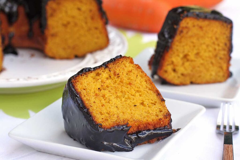 duas fatias de bolo de cenoura com cobertura de chocolate, a do prato da frente está deitada no prato, a de trás está de pé