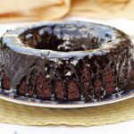 bolo redondo com furo no meio com cobertura de chocolate cremosa escorrendo por cima