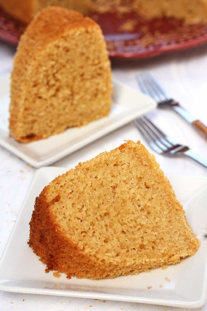 Duas fatias de bolo de aveia, a da frente está deitada sobre prato quadrado pequeno e a de trás está de pé, tem dois garfinhos ao lado
