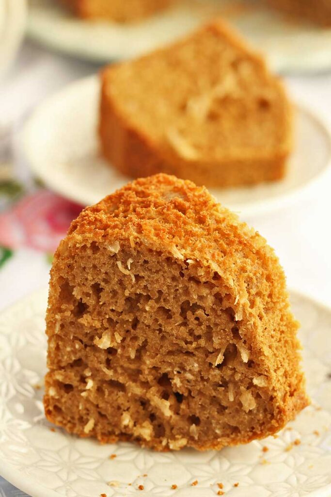 Duas fatias de bolo de coco, a fatia da frente está de pé e a de trás está deitada