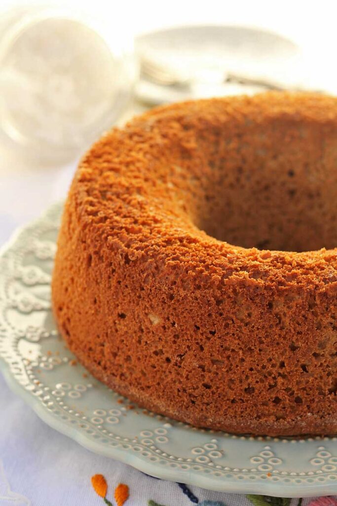 bolo redondo com furo no meio sobre prato redondo com detalhes em alto relevo na borda