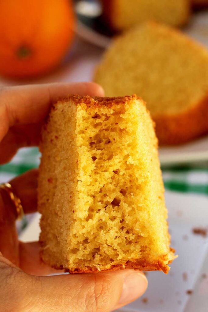 mão segurando fatia de bolo de laranja fofinho já mordido