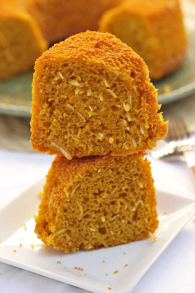 Fuas fatias de bolo de abóbora com coco sobrepostas em um prato quadrado pequeno
