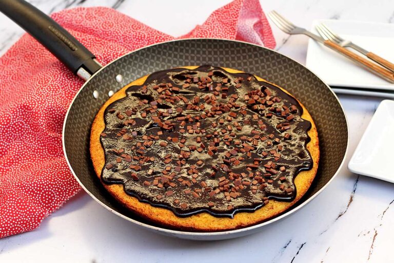 Frigideira antiaderente com bolo de cenoura dentro, esse bolo tem cobertura de chocolate e granulado de chocolate por cima