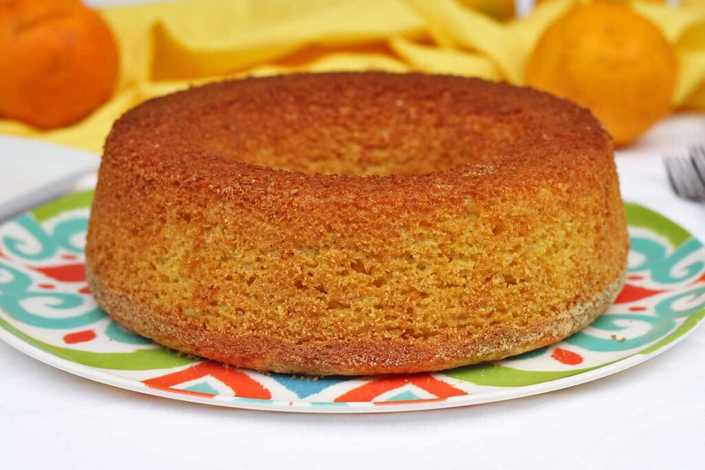 Bolo redondo com furo no meio e laranjas ao fundo