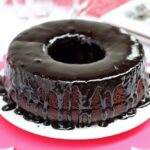 Bolo redondo com furo no meio de café com chocolate, cobertura cremosa e brilante escorrendo pelas laterais do bolo