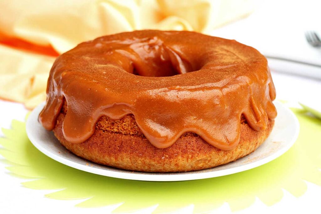 Bolo redondo com furo no meio com doce de leite cremoso e bem generoso por cima